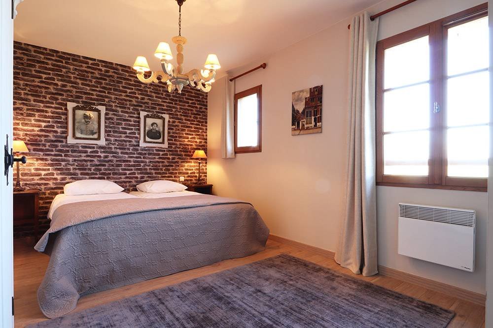 Slaapkamer met bakstenen wand en kroonluchter